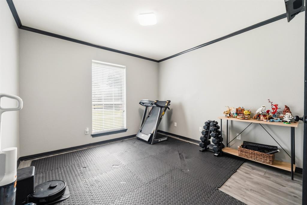10512 Whitney Trace Drive Waco, TX 76708 - Photo 35 of 39 Versatile room featuring light grey walls with contrasting dark trim, a single window with blinds, and a combination of interlocking rubber mat flooring and wood-finish flooring