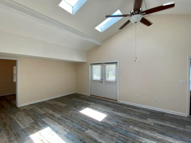 an empty room with wooden floor closet and windows