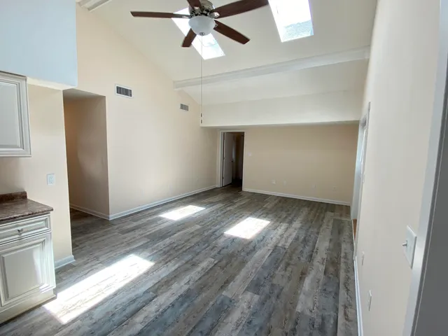 a view of an empty room with wooden floor and a window