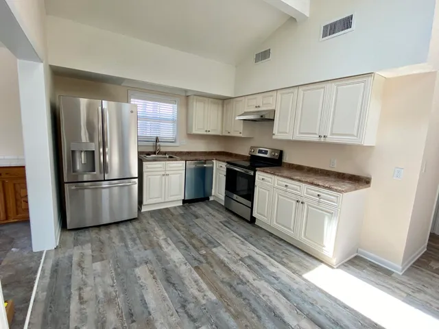 a kitchen with granite countertop a refrigerator and a stove top oven