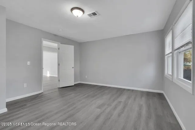 an empty room with wooden floor cabinet and windows