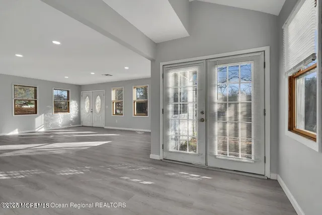 a kitchen with stainless steel appliances granite countertop a stove top oven a sink a refrigerator and white cabinets with wooden floor