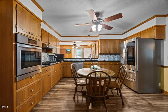 a kitchen with stainless steel appliances kitchen island granite countertop a table chairs in it and wooden floors