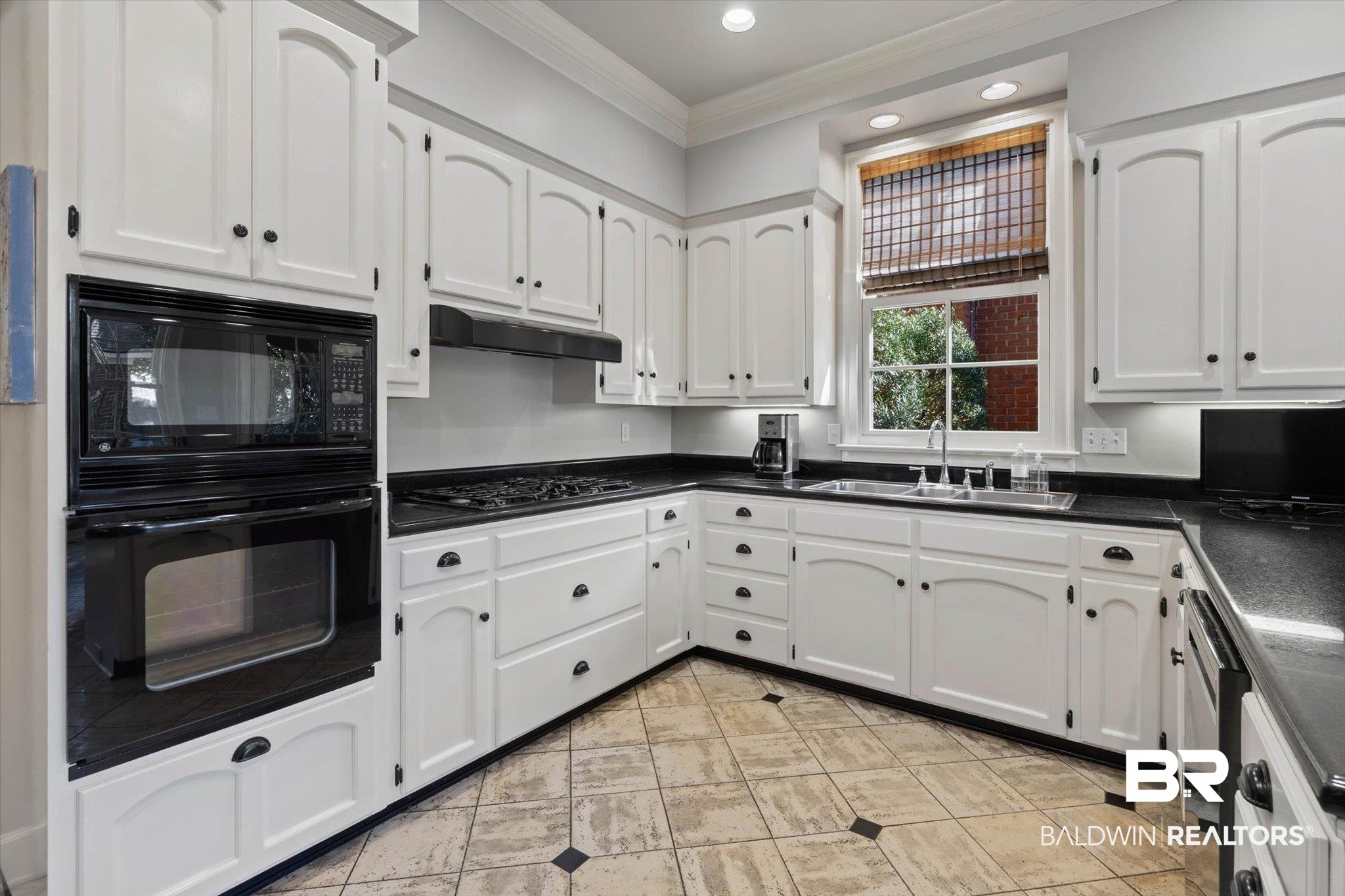 3615 Stein Street Mobile, AL 36608 - Photo 12 of 44 Kitchen with dark countertops, black appliances, ornamental molding, white cabinetry, and under cabinet range hood