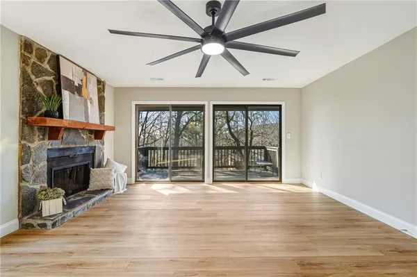 a view of an empty room with wooden floor and a fireplace