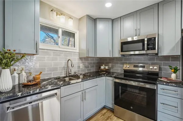 a kitchen with granite countertop a stove sink and microwave