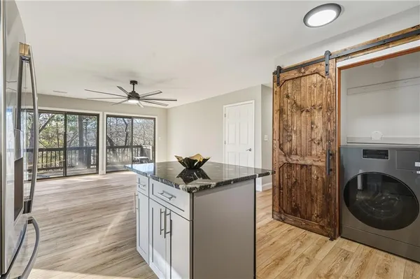 a kitchen with a stove a refrigerator and a view of living room