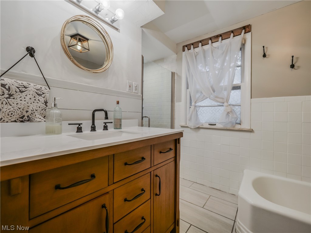 2378 Charney Road Cleveland, OH 44118 - Photo 19 of 28 Bathroom with tile walls, a bathing tub, large vanity, and tile floors