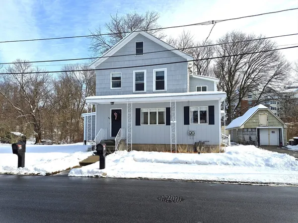 a front view of a house with a dirt yard and a large tree
