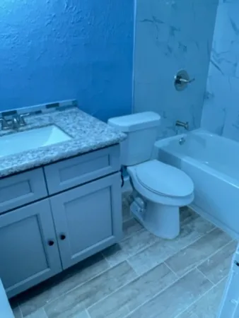 a bathroom with a granite countertop toilet and a sink