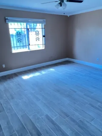 an empty room with wooden floor and windows