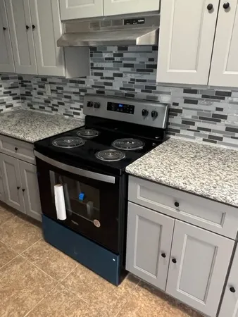 a kitchen with white cabinets and a stove