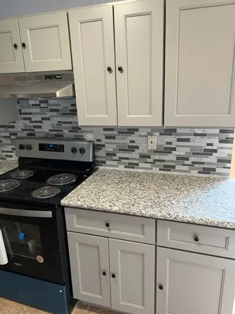 a kitchen with granite countertop a stove sink and cabinets