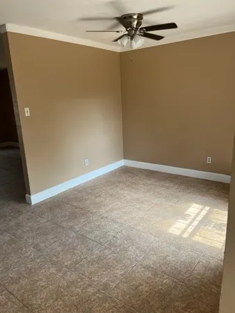 an empty room with a ceiling fan and window