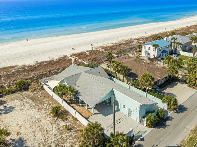 an aerial view of ocean and residential houses with outdoor space