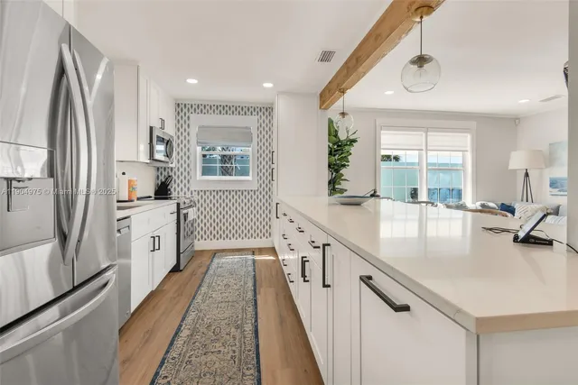 a kitchen with white cabinets and window