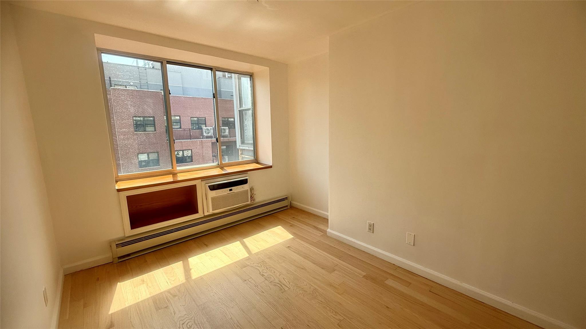 43-17 Union Street, Unit 6C Queens, NY 11355 - Photo 11 of 16 Unfurnished room featuring baseboard heating, wood finished floors, and a wall unit AC