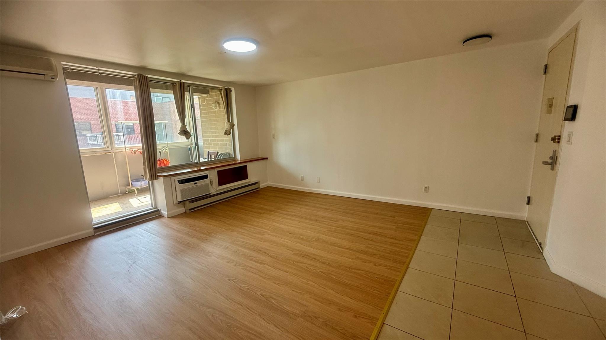 43-17 Union Street, Unit 6C Queens, NY 11355 - Photo 15 of 16 Unfurnished room with wood finished floors, a wall mounted air conditioner, baseboard heating, and a wall mounted AC