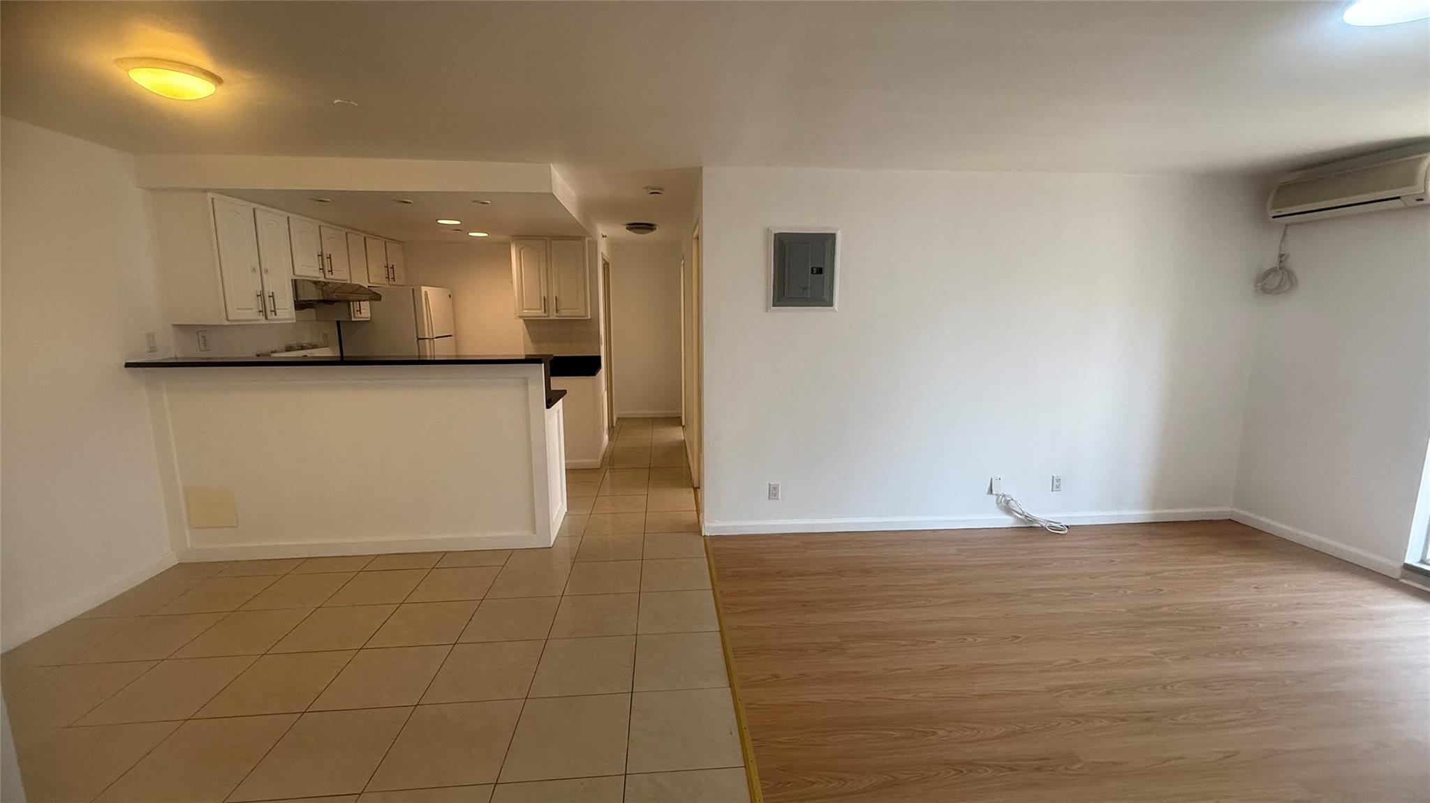 43-17 Union Street, Unit 6C Queens, NY 11355 - Photo 3 of 16 Kitchen featuring an AC wall unit, electric panel, freestanding refrigerator, dark countertops, and light tile patterned flooring