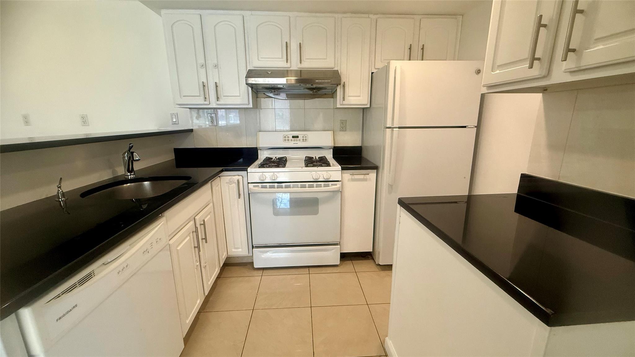 43-17 Union Street, Unit 6C Queens, NY 11355 - Photo 7 of 16 Kitchen featuring white appliances, under cabinet range hood, white cabinetry, and dark countertops