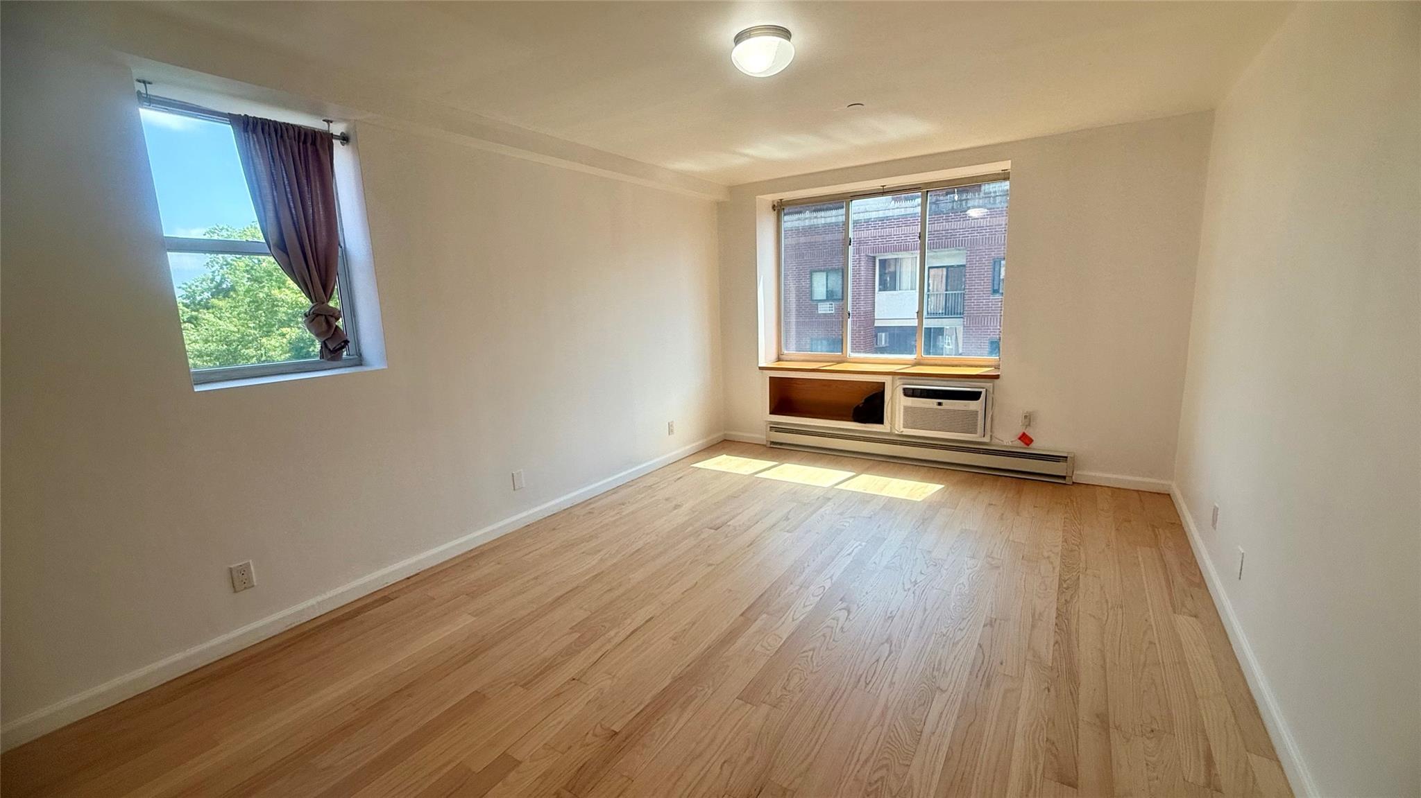 43-17 Union Street, Unit 6C Queens, NY 11355 - Photo 9 of 16 Empty room with baseboard heating and light wood finished floors
