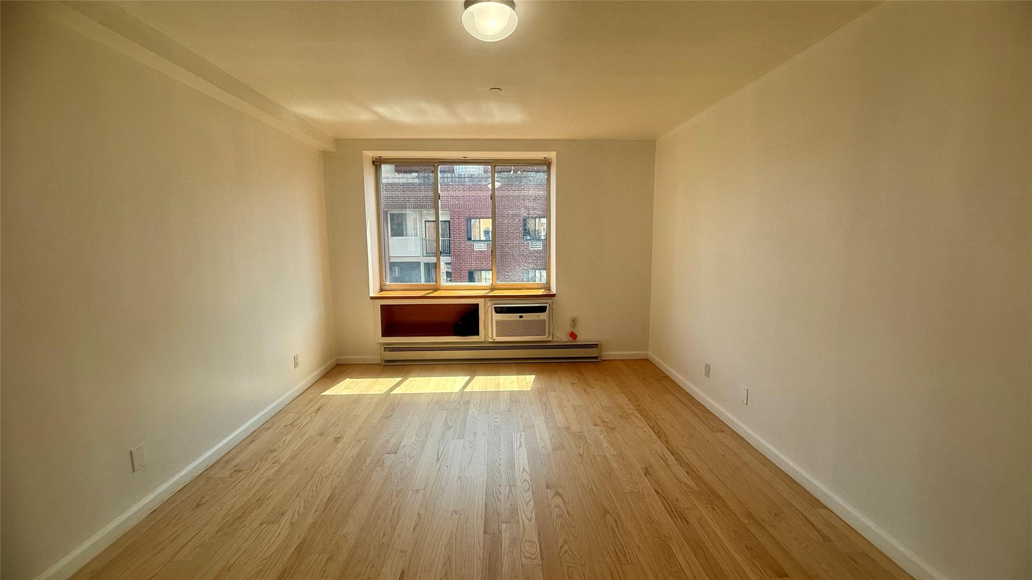 43-17 Union Street, Unit 6C Queens, NY 11355 - Photo 10 of 16 Spare room with light wood-style flooring, a baseboard radiator, and an AC wall unit