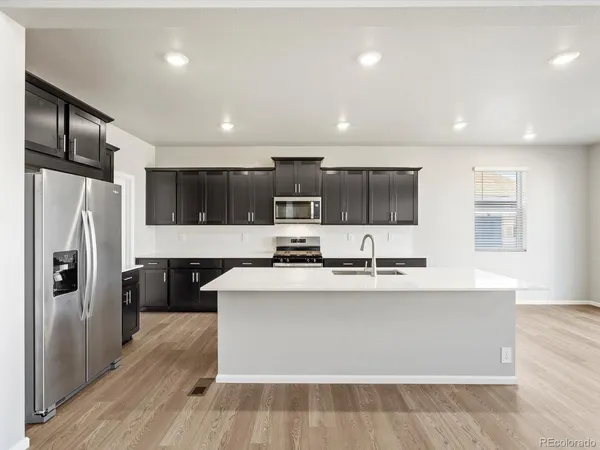a large kitchen with stainless steel appliances a large counter top a stove and a refrigerator