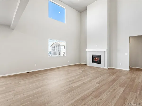 an empty room with wooden floor fireplace and windows