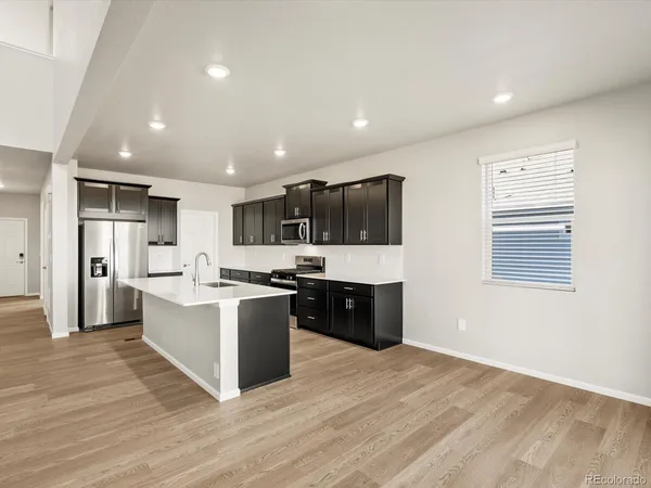 a large kitchen with stainless steel appliances kitchen island a large counter top and a wooden floors
