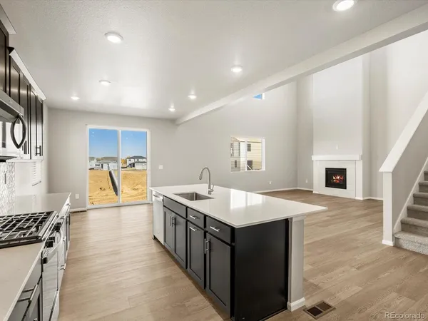 a kitchen with a stove a sink dishwasher and a refrigerator with wooden floor
