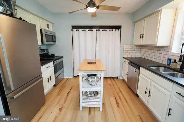 a kitchen with a sink a stove and white cabinets with wooden floor