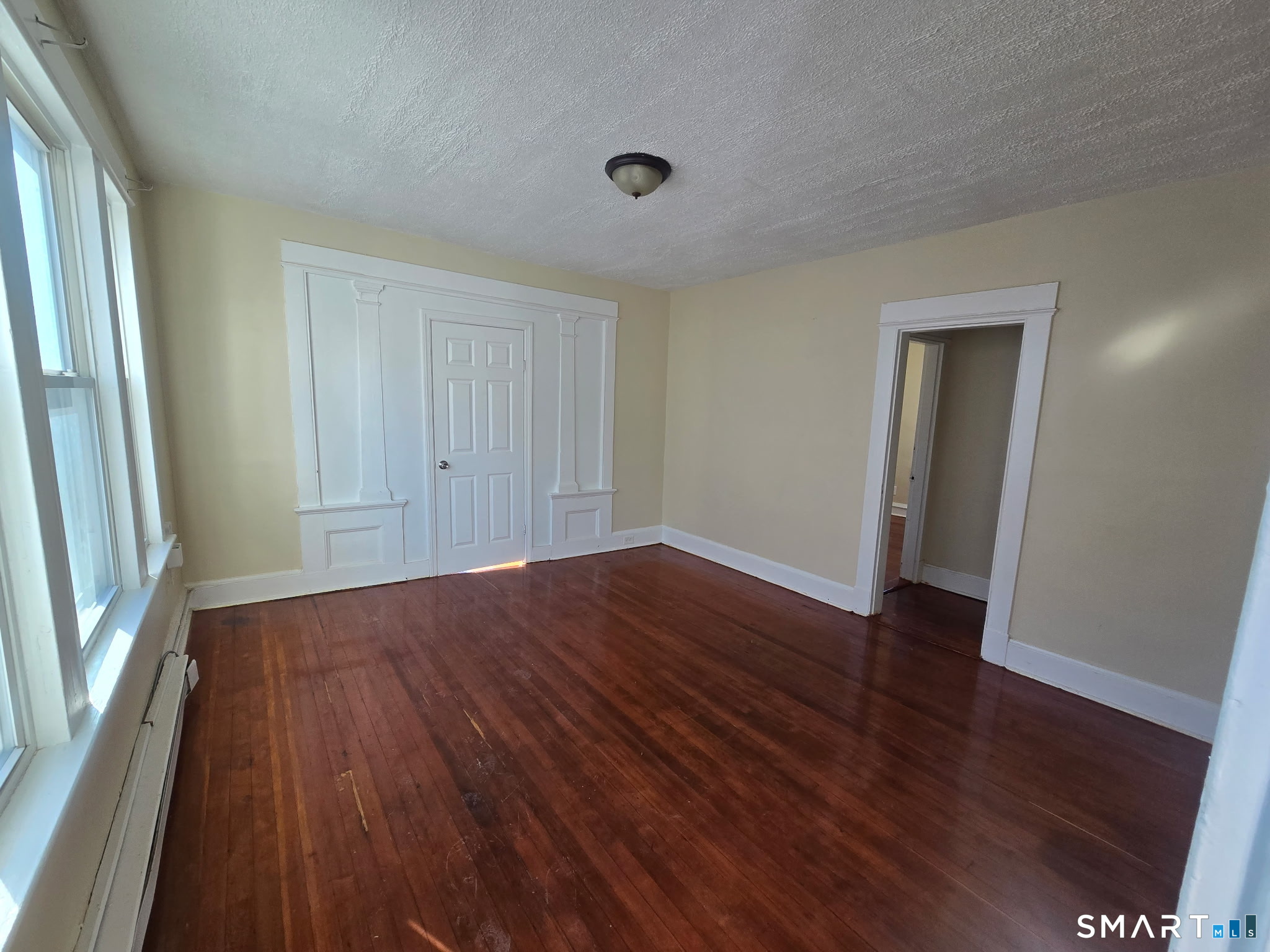 an empty room with wooden floor and a window