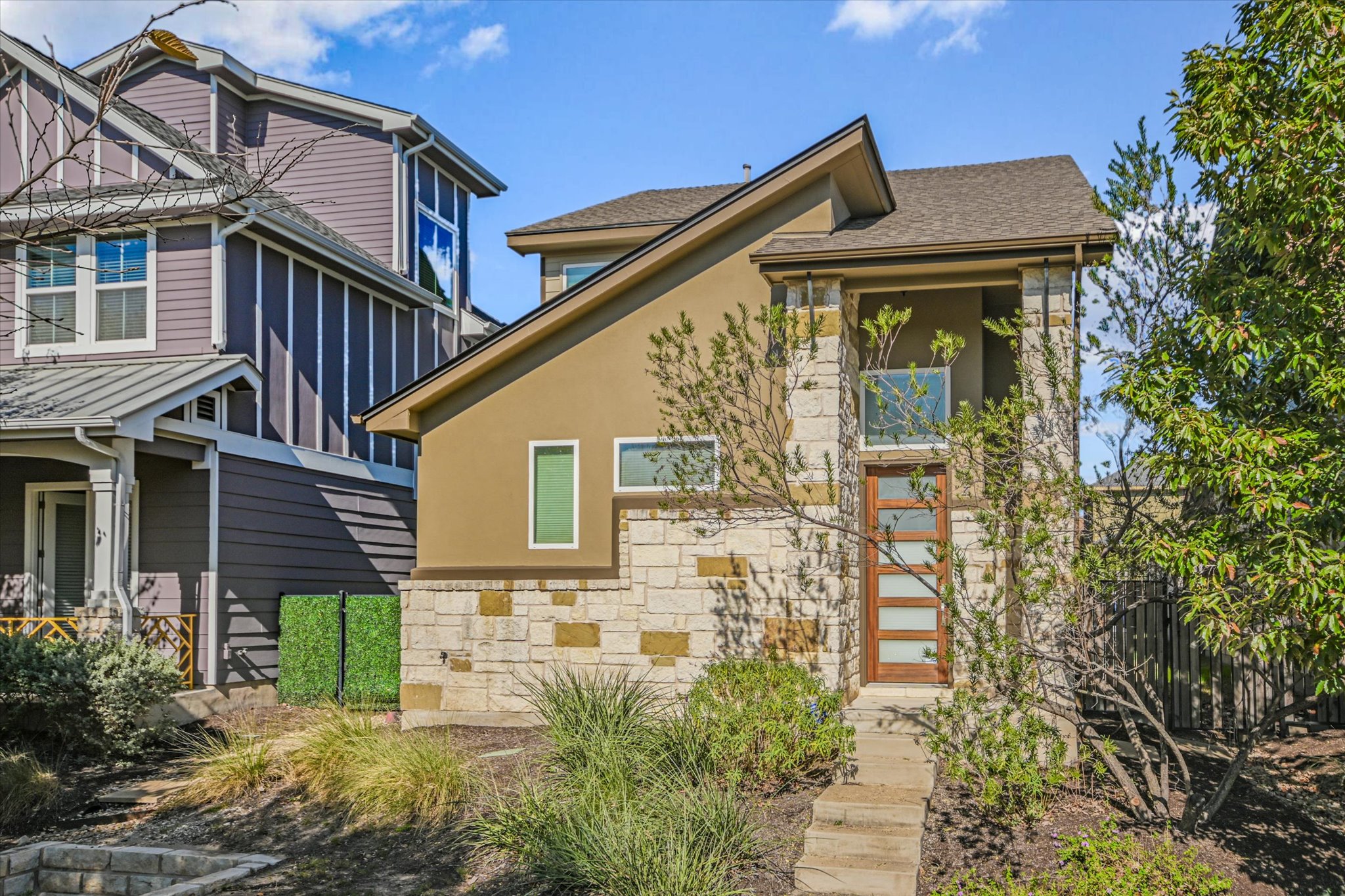 View of front of house featuring stucco siding, stone siding, and roof with shingles