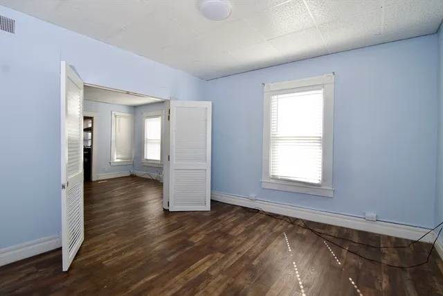 an empty room with wooden floor and windows