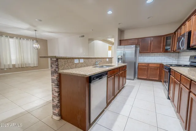 a kitchen with stainless steel appliances granite countertop a stove a sink dishwasher and a refrigerator
