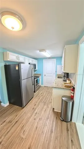 a kitchen with granite countertop a refrigerator a stove and a wooden floors