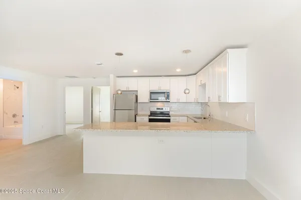 a large white kitchen with kitchen island a stove a sink a refrigerator and white cabinets