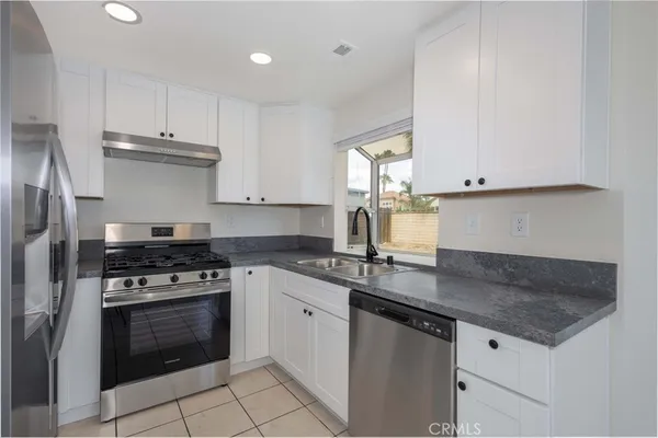 a kitchen with granite countertop a stove sink and cabinets
