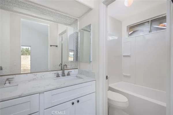 a bathroom with a granite countertop sink a toilet and a bathtub