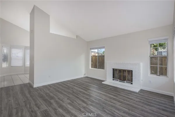 an empty room with wooden floor a fireplace and windows