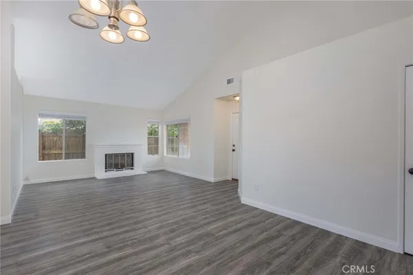an empty room with wooden floor cabinet and windows