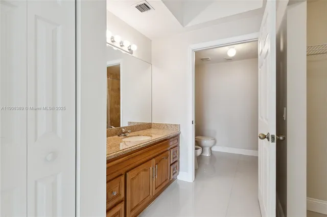 a bathroom with a granite countertop sink a toilet and a mirror
