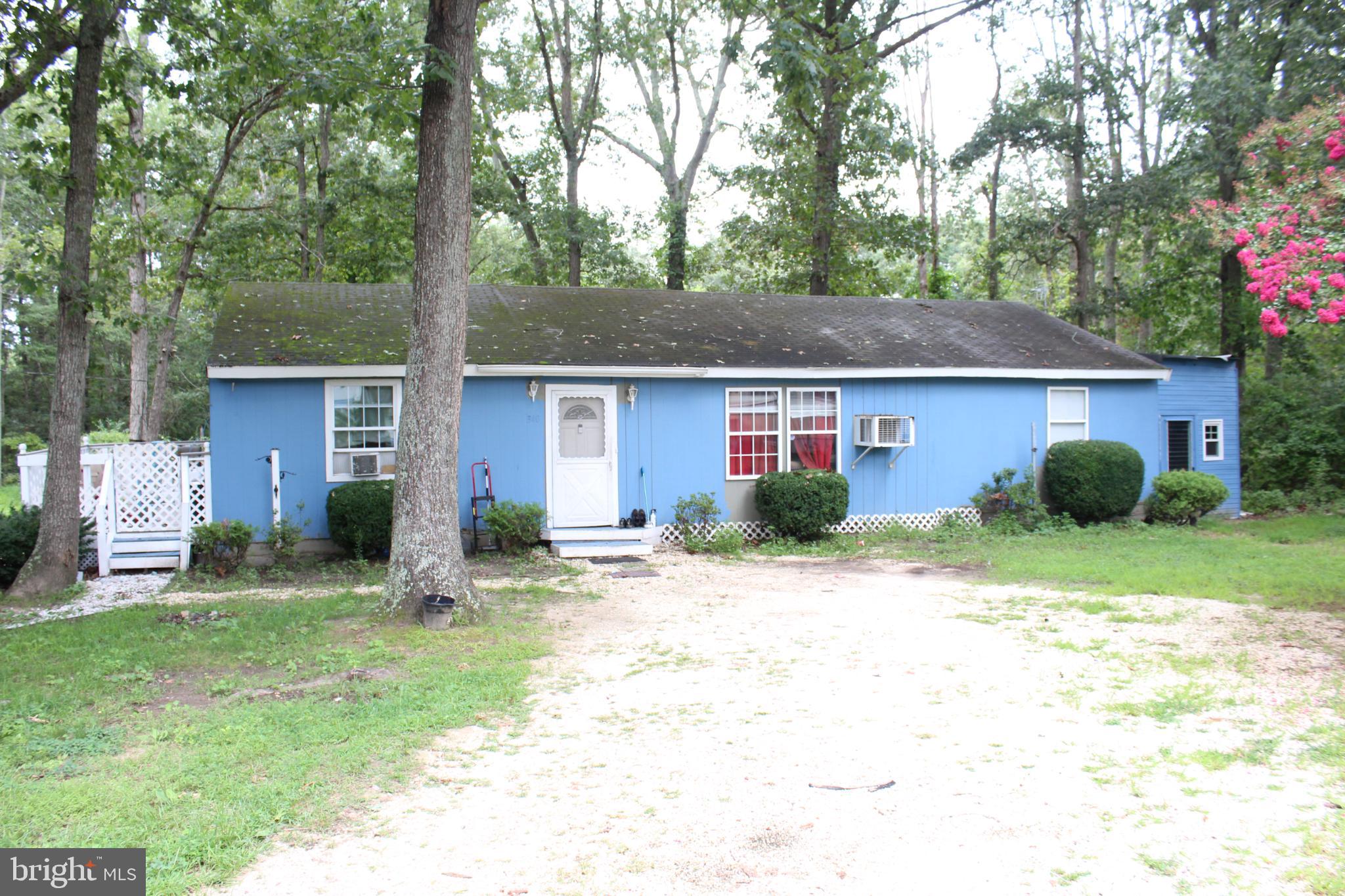 Charming blue home nestled among trees.