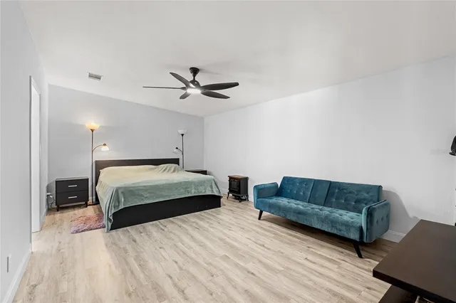 a spacious bedroom with a bed a couch and a ceiling fan