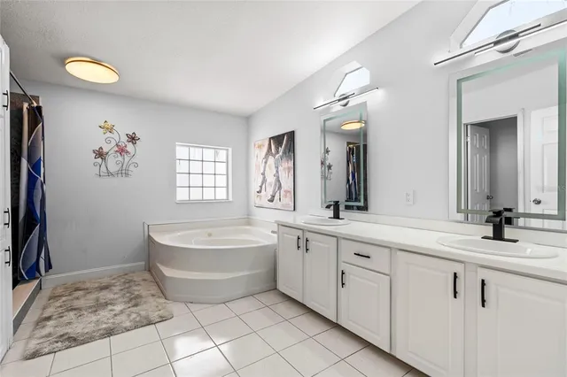 a spacious bathroom with a double vanity sink a mirror and a bathtub