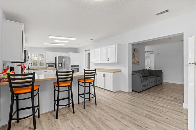 a kitchen with stainless steel appliances kitchen island wooden floors and white cabinets