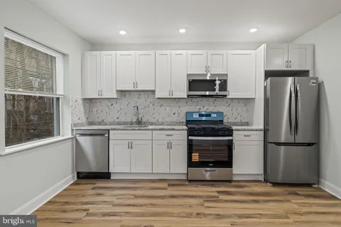 a kitchen with a refrigerator stove and white cabinets