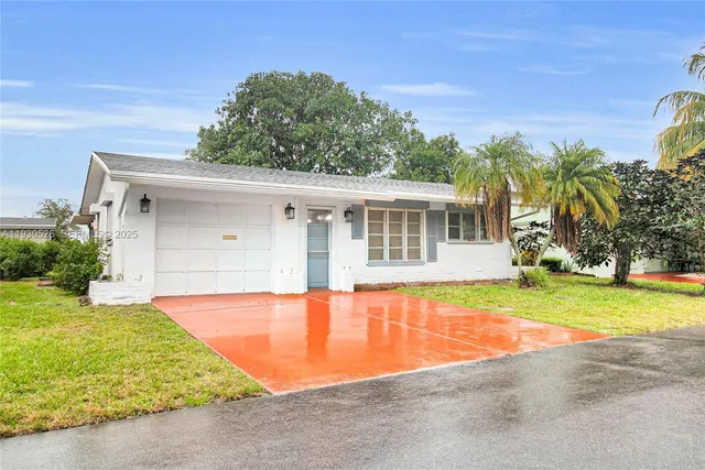 front view of house with a yard and palm trees