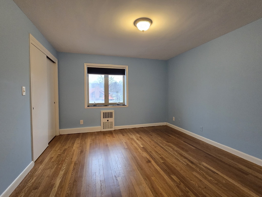 114 Pleasant Street, Unit 306 Arlington, MA 02476 - Photo 11 of 16 an empty room with wooden floor and windows