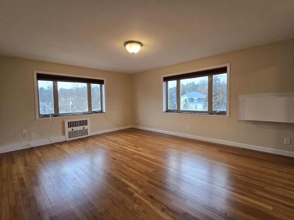 114 Pleasant Street, Unit 306 Arlington, MA 02476 - Photo 3 of 16 a view of an empty room with wooden floor and a window
